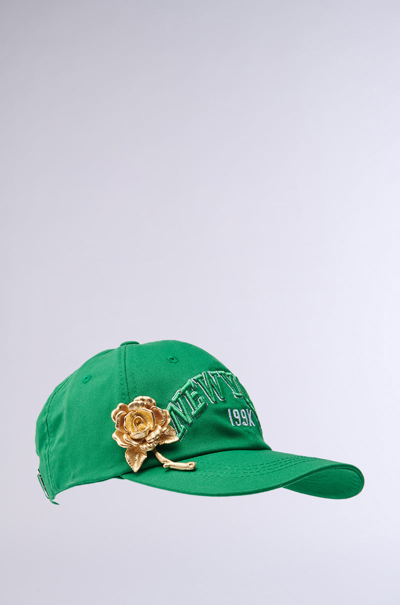 The THIS IS MY CITY HAT is a stylish green baseball cap with "NEW YORK 199X" embroidered and a gold metallic rose on the brim. It includes an adjustable strap and is elegantly displayed against a light gray background. 3