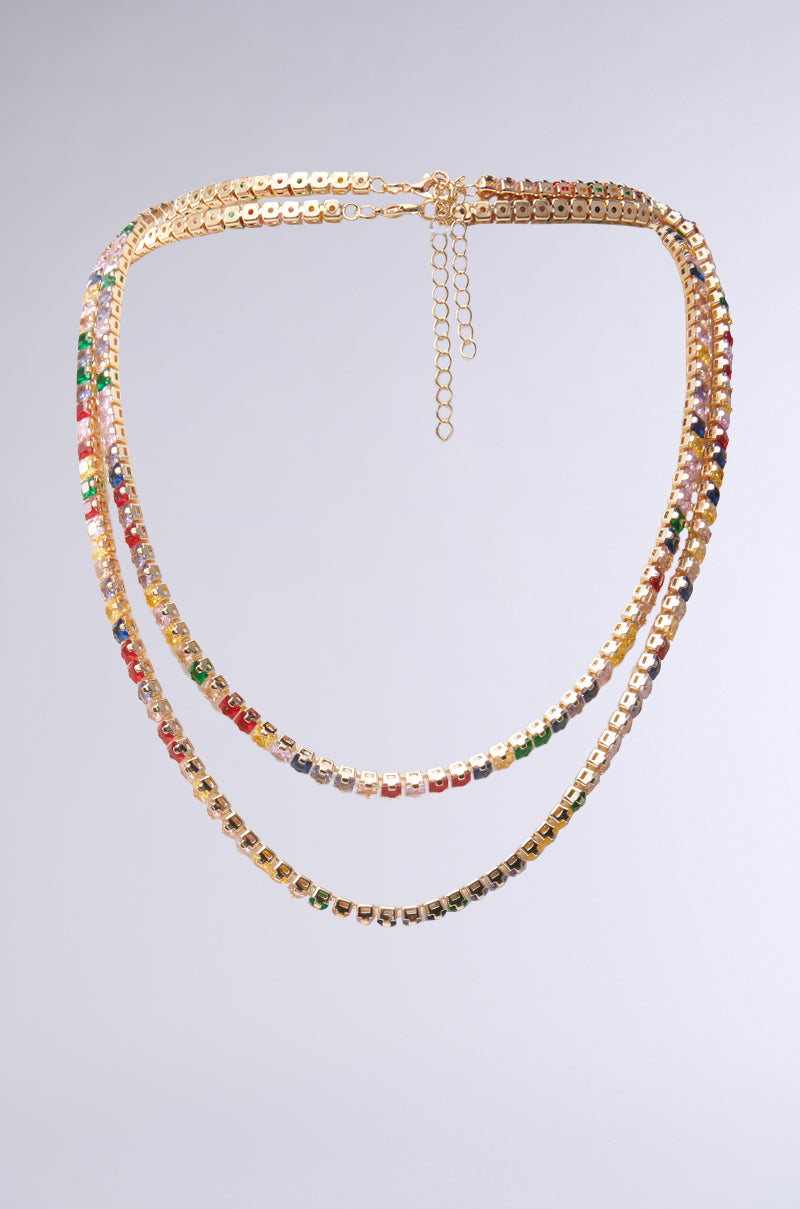 The HARD CANDY NECKLACE SET features two layered gold chains with small, square multicolored jewels and secure lobster clasps, displayed on a plain light gray background.