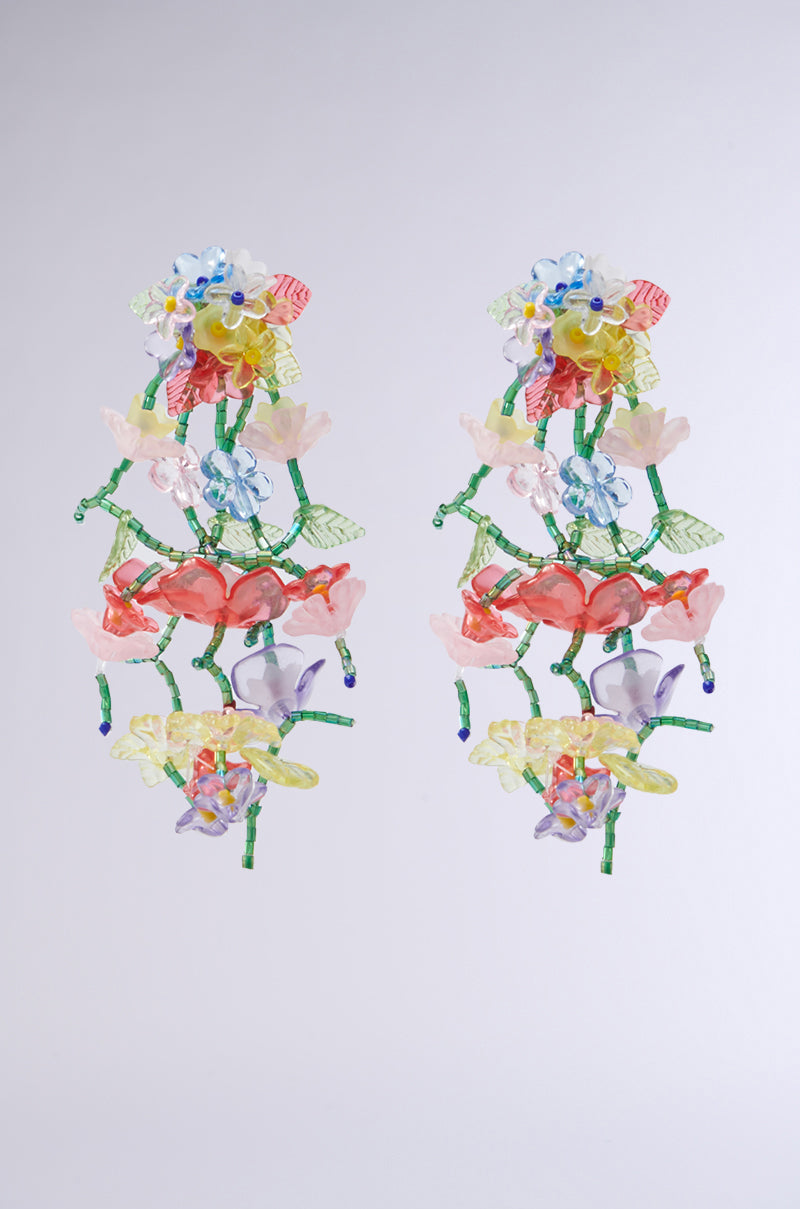 The ENLIGHTEN ME EARRING showcases intricate chandelier designs with cascading floral and butterfly motifs crafted from vibrant glass beads in pink, blue, yellow, and green.