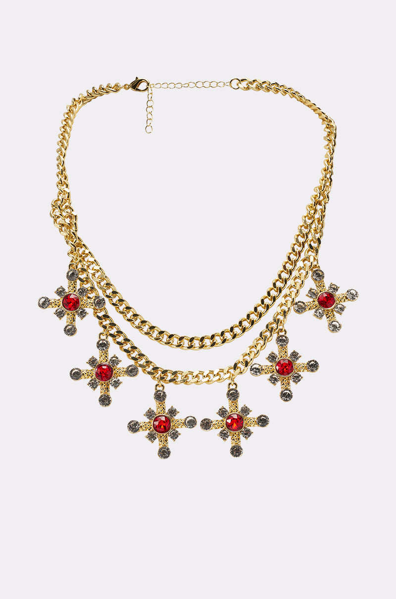 The MAXIMUM GLAM NECKLACE is a gold layered chain with two tiers, featuring seven rhinestone cross pendants adorned with red and clear gems, evenly spaced along the lower tier for an elegant touch. 0