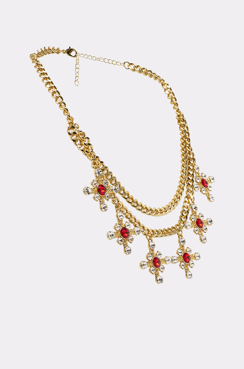 The MAXIMUM GLAM NECKLACE is a gold layered chain with two rows and five cross crystal charms in red and clear stones. It features an adjustable clasp and a shiny finish for a chic look. 2