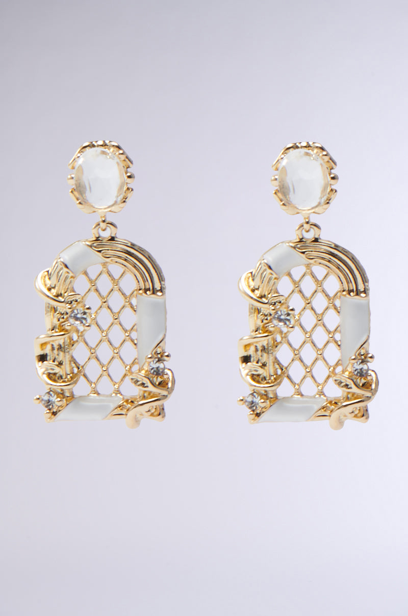 The OUTTA THE WAY GOLD EARRING features an ornate lattice design with white enamel and sparkling crystals, plus elegant scrollwork that adds vintage charm, shown on a plain light gray background.