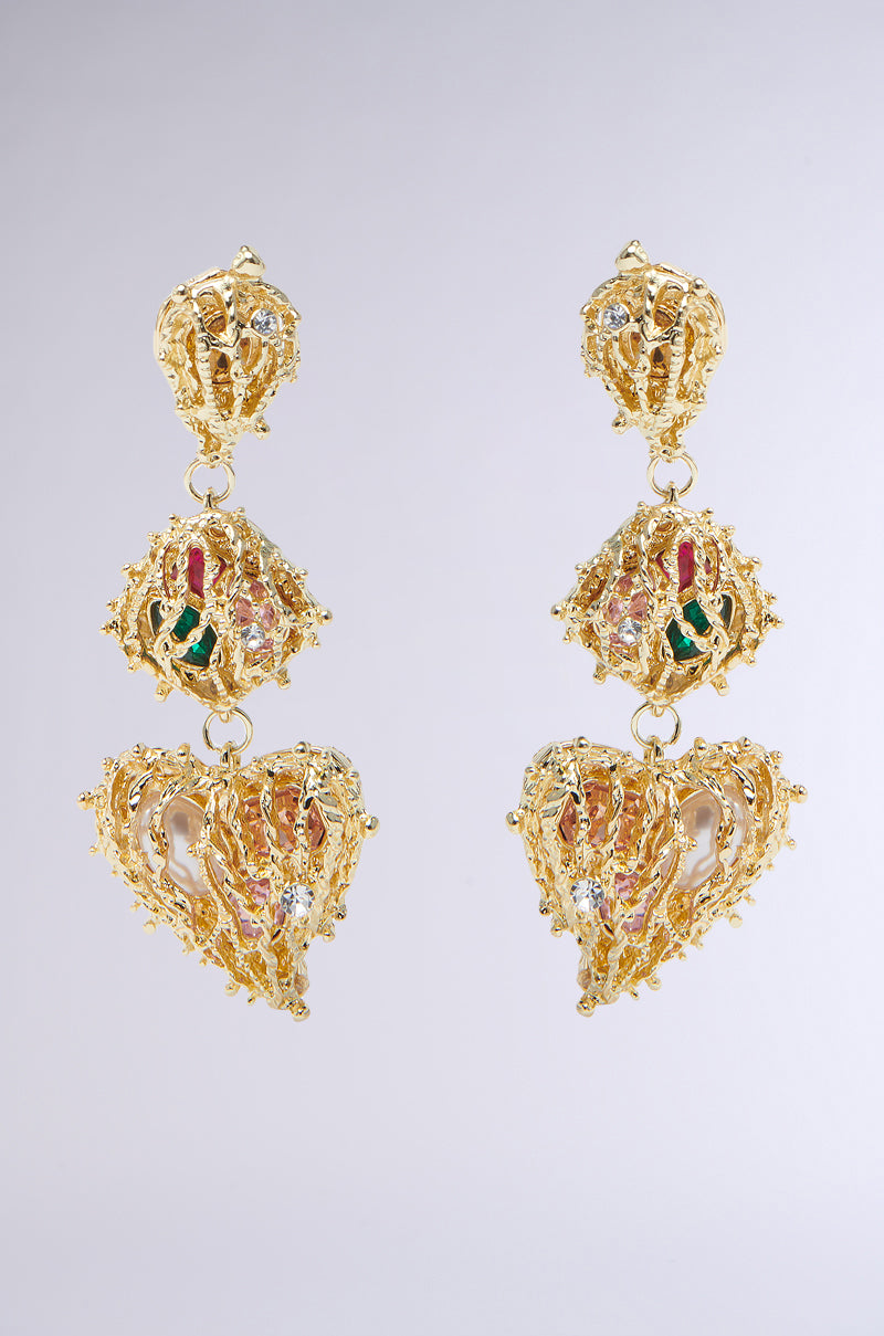 The TAKE MY HEART DROP EARRING features an ornate design with three sections: a round top, an intricate middle adorned with colorful accents, and a heart-shaped bottom, all set against a simple gray background that highlights their elegance.