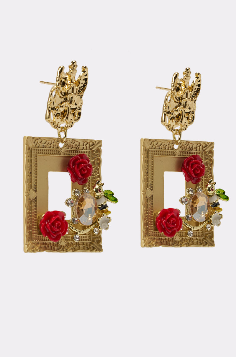 PICTURE PERFECT EARRING: Gold rectangular frame earrings feature ornate detailing with red rose accents, clear teardrop crystals, green leaves, and floral motifs. They have a stud backing with an elegant gold design. 2