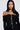 A woman with long dark hair wears an off-the-shoulder black sweater and the DRIPPIN PEARLZ NECKLACE adorned with pearlescent beads. She stands against a plain white background, looking directly at the camera.