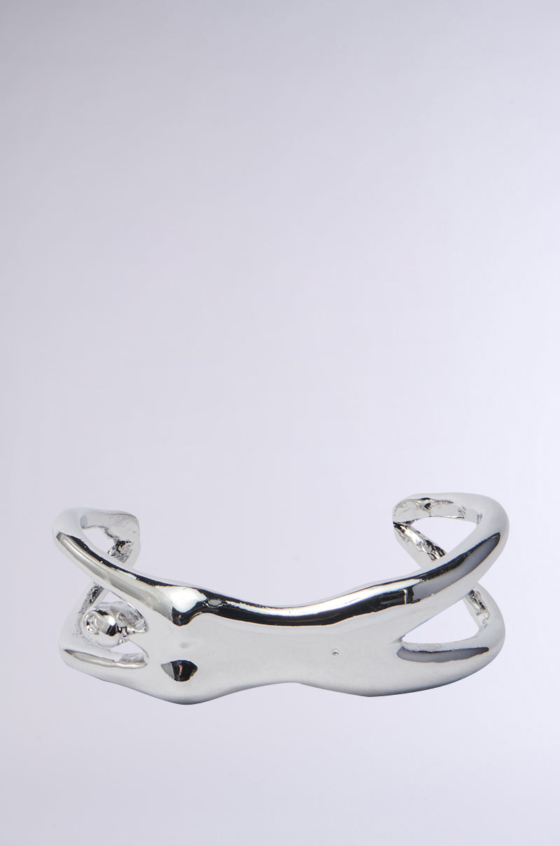 The I AM EVERYTHING BRACELET by AKIRA Label features a polished, abstract twisted design in faux silver metallic against a plain gray backdrop.