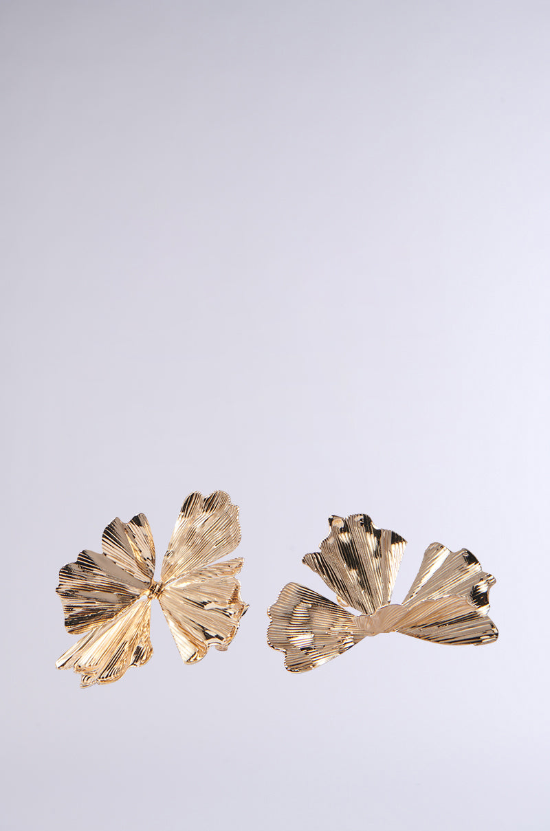 Two asymmetrical fan-like earrings with textured, ribbed, faux gold surfaces rest on a plain gray background, resembling delicate botanical leaves or petals. They are part of the IN BLOOM RING SET, capturing nature's elegance.