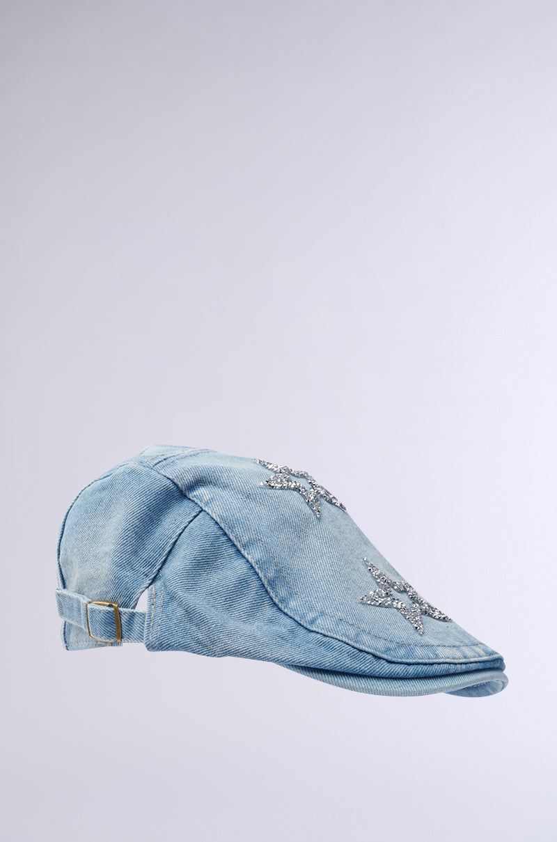 The MARDIE GURL HAT is a light denim scally cap set against a gray background, adorned with rhinestone star embellishments, and features an adjustable back strap for a perfect fit. 2