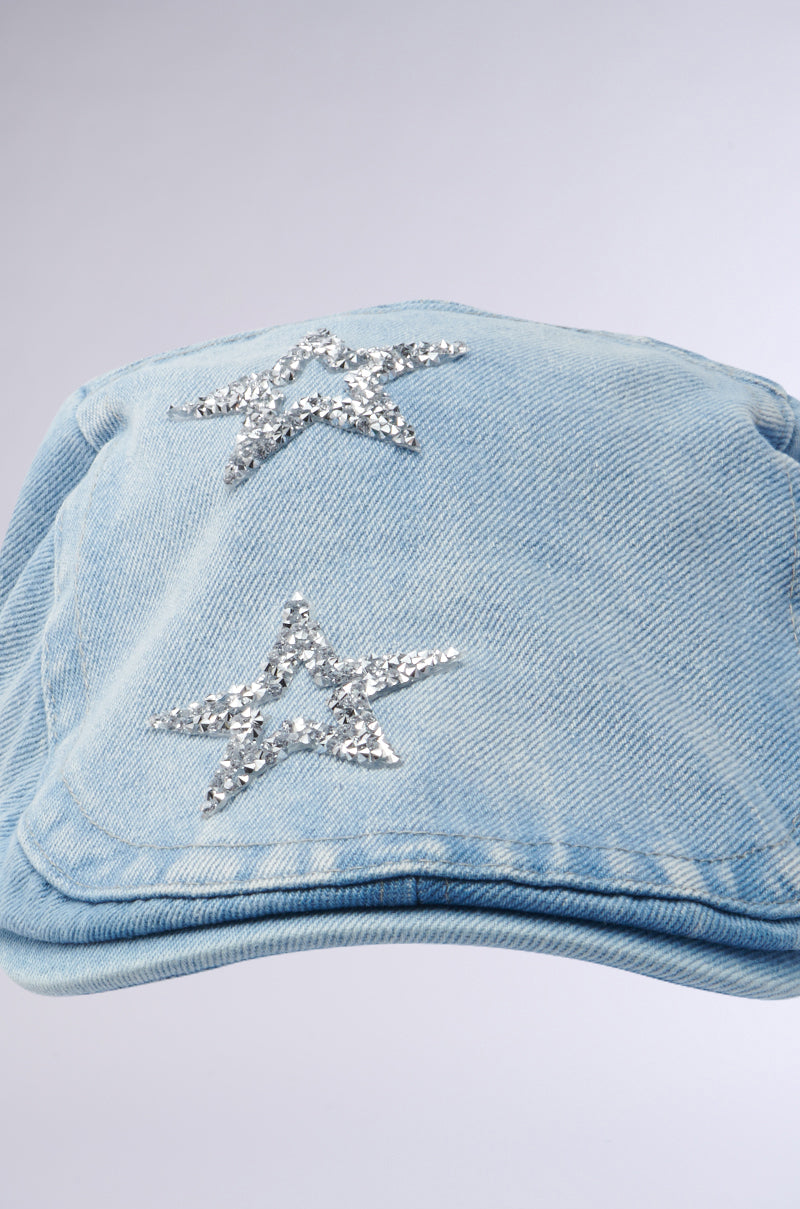 The MARDIE GURL HAT is a light blue denim scally cap adorned with two rhinestone star embellishments, set against a plain gray background. 3