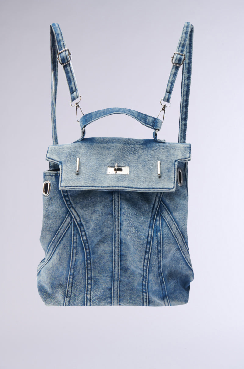 The KEEP EM ALL BACKPACK is a blue denim bag with adjustable shoulder straps, a top handle, and a front flap with a silver clasp. Vertical stitching and its faded blue tone make it an ideal choice for any casual outing. 0
