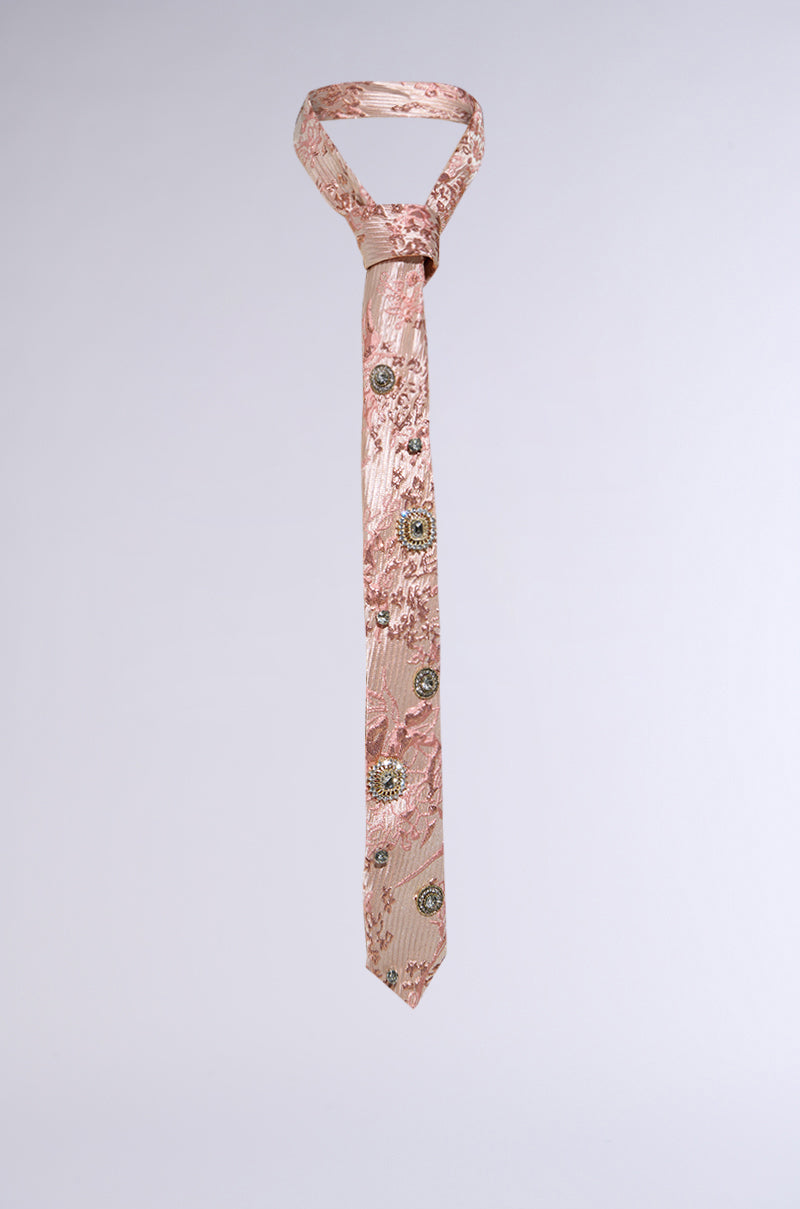 The LIVE FOR IT EMBELLISHED TIE is a pink necktie with intricate embroidery and shimmering metallic jewels in a brocade pattern, featuring textured floral and circular motifs on a plain background.