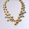 Introducing the POP BUBBLY NECKLACE: two strands of bubble-like beads in metallic silver and gold finishes, with varying sphere sizes for texture, elegantly completed with a chain clasp against a simple light gray background.