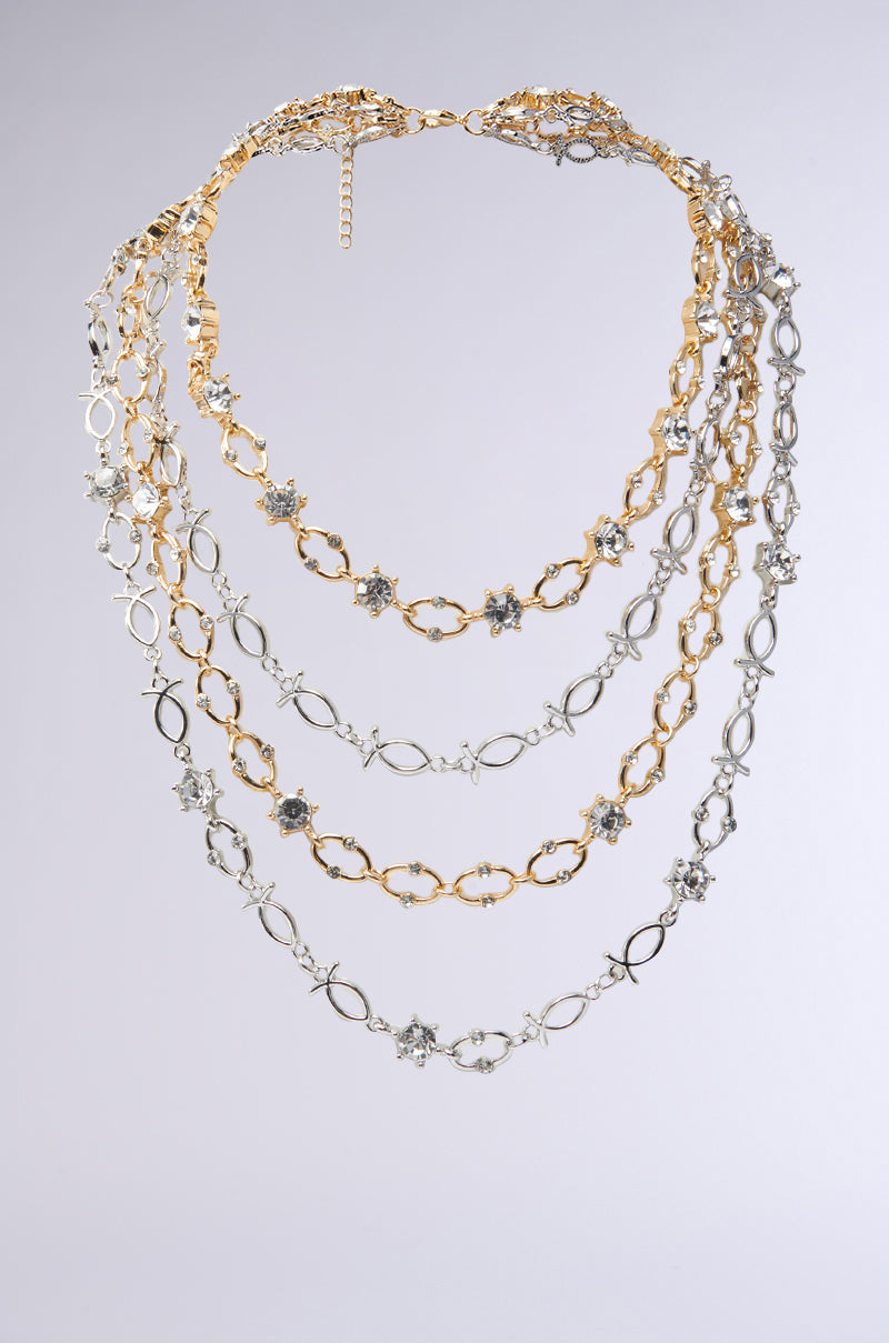 The STUNNA LAYERED NECKLACE features four layers with gold and silver chain links, sparkling rhinestones, and star-shaped embellishments, creating an elegant cascading effect.