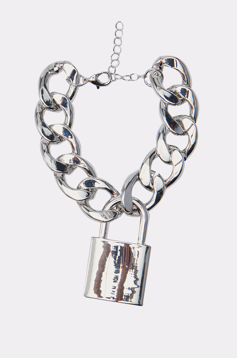 The LOVE LOCKDOWN SILVER BRACELET features a chunky silver chain with a shiny padlock charm and adjustable clasp, styled like a bold chain link, shown on a plain white background. 0