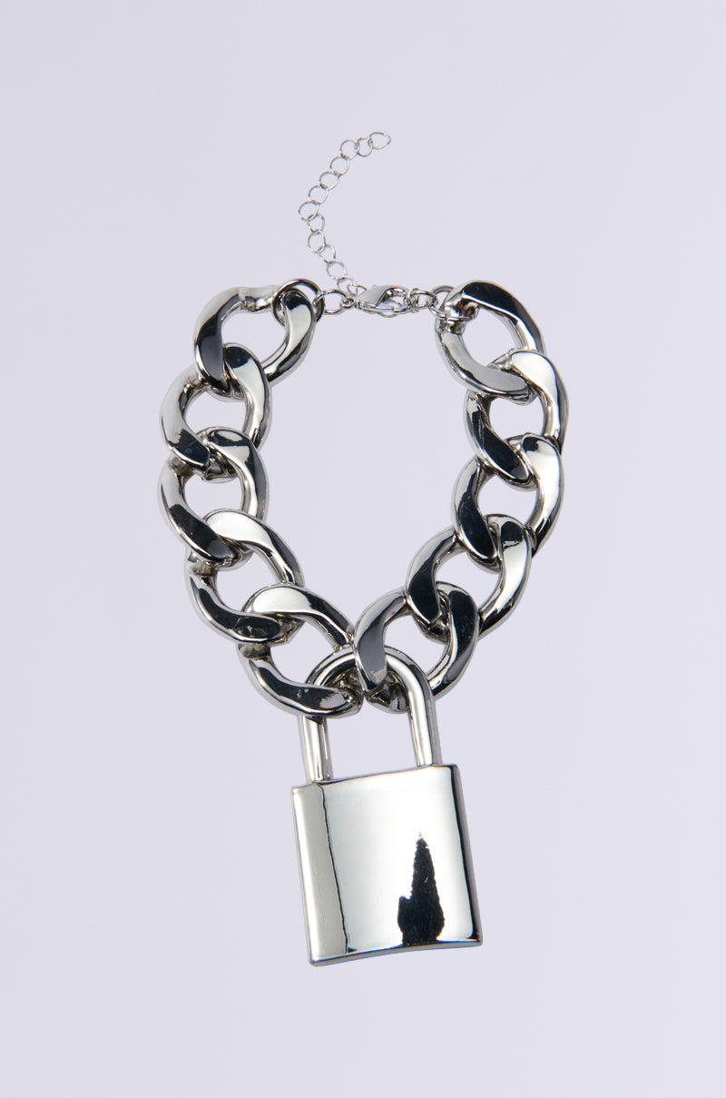 The LOVE LOCKDOWN SILVER BRACELET is a versatile accessory with chunky interlocking silver links and a shiny padlock pendant. It features an adjustable chain, making it stand out beautifully against any plain gray background. 1