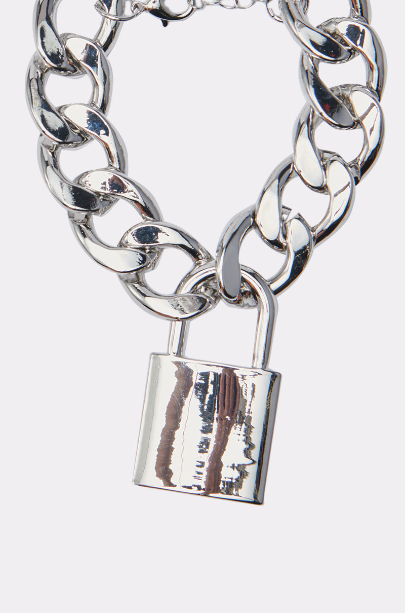 The LOVE LOCKDOWN SILVER BRACELET is a chunky metallic faux silver chain featuring a large, shiny padlock pendant, displayed on a plain white background. 2