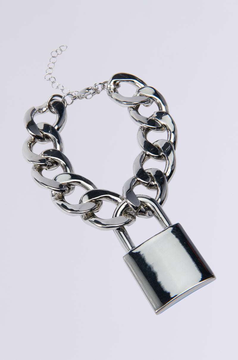 The LOVE LOCKDOWN SILVER BRACELET is a versatile chunky chain link accessory featuring a silver padlock pendant as its striking centerpiece. It includes an adjustable clasp for the perfect fit and is displayed against a plain white background. 4