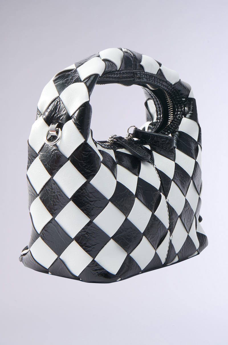 The SPLIT DECISION PU PURSE is a stylish black and white checkered handbag with a soft, woven texture, round handle, and visible zipper, shown against a plain light gray background.