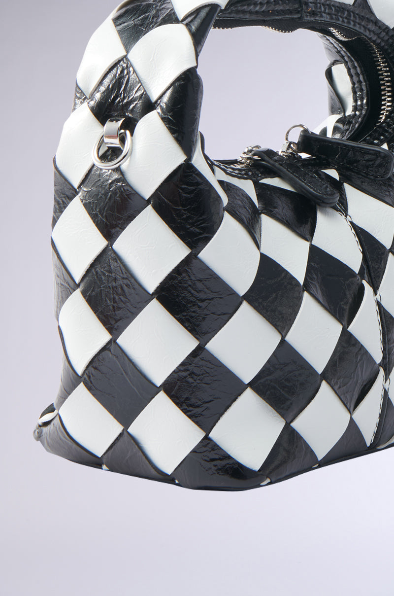 Close-up of the SPLIT DECISION PU PURSE featuring a black and white checkered pattern, textured PU material, and metal ring detail near the handle. The stylish, modern bag is shown against a light background.