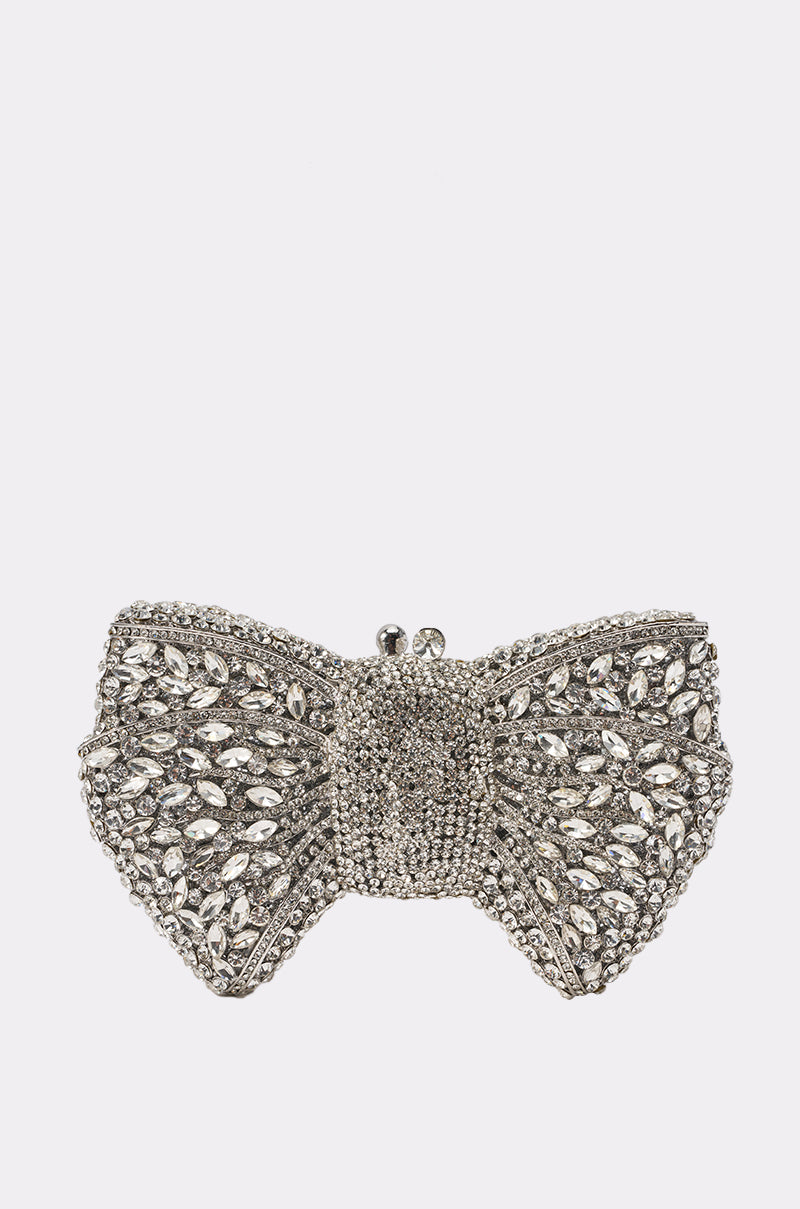 The BLING BAG, a sparkling mini clutch shaped like a silver bow and adorned with dazzling rhinestones and beads, features a metallic top clasp and is displayed against a plain white background—the ultimate party girl accessory.