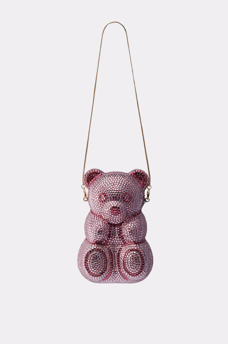 The YUMMY GUMMY BLING BAG is a pink rhinestone handbag shaped like a teddy bear, featuring a thin gold shoulder strap that sparkles against a plain white background.