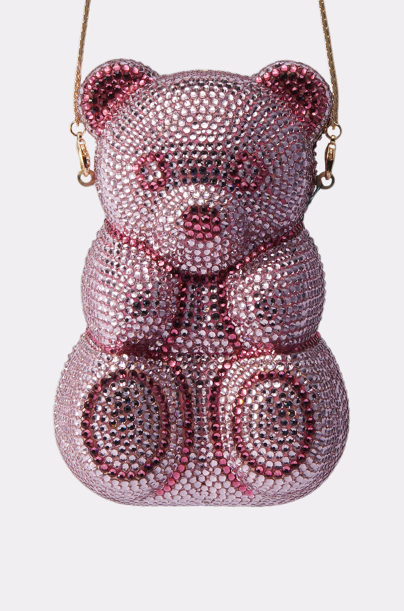 The YUMMY GUMMY BLING BAG is a pink teddy bear-shaped handbag adorned with sparkling rhinestones and a stylish gold shoulder strap.