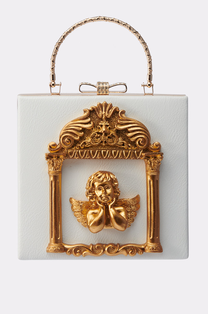 The IM AN ANGEL PURSE is a white rectangular faux leather handbag featuring a Baroque-inspired gold cherub and wing design on the front, with an ornate frame and decorative gold handle for a touch of vintage glamour. 0
