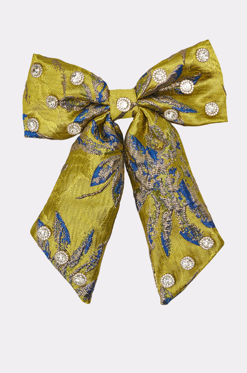 The LETS GO EMBELLISHED HAIR BOW is a decorative gold statement hair clip with blue and silver floral designs and circular rhinestone details, displayed on a plain white background. 1