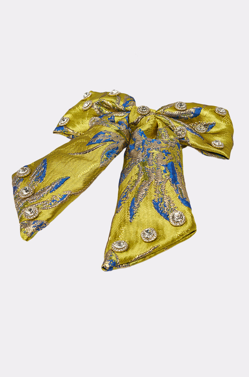 The LETS GO EMBELLISHED HAIR BOW is a yellow statement clip featuring blue and silver embroidery plus sparkling silver buttons, shown on a plain white background. 2