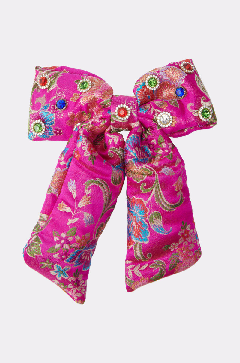 The CICI DREAMS HAIR CLIP features a vibrant pink satin bow with a gold, blue, and green floral pattern, adorned with red, green, and blue gemstones for an elegant decorative touch. 3