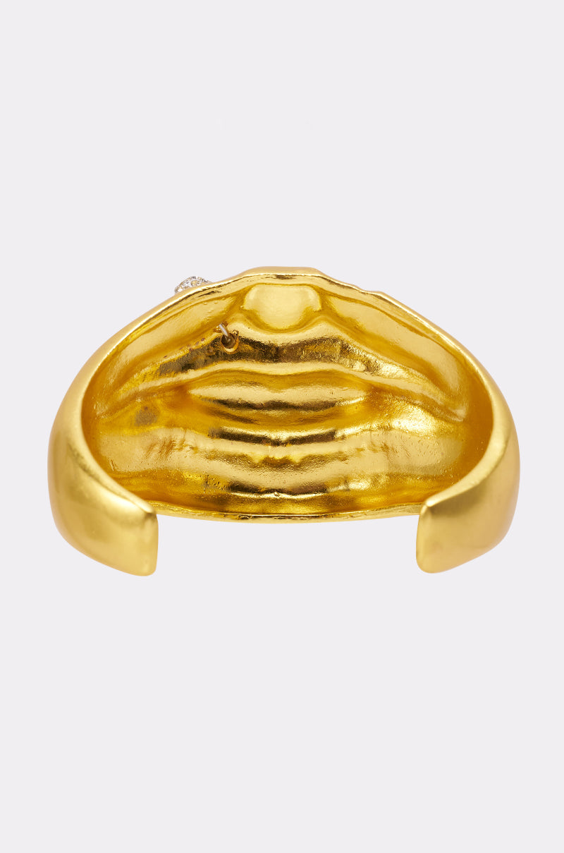 The RAWR BRACELET is a gold sculptural cuff with a central lips-inspired design, displayed against a plain light background. 3