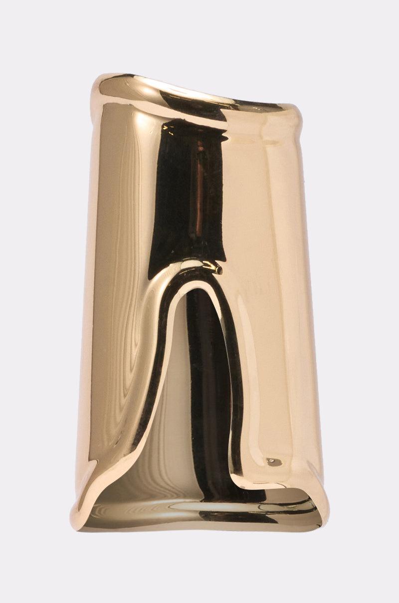 The OUTFIT COMPLETER CUFF features a shiny gold metallic finish, an irregular wavy shape, and a smooth, reflective surface, resembling a sculptural accessory or bold statement cuff against a light gray background. 0