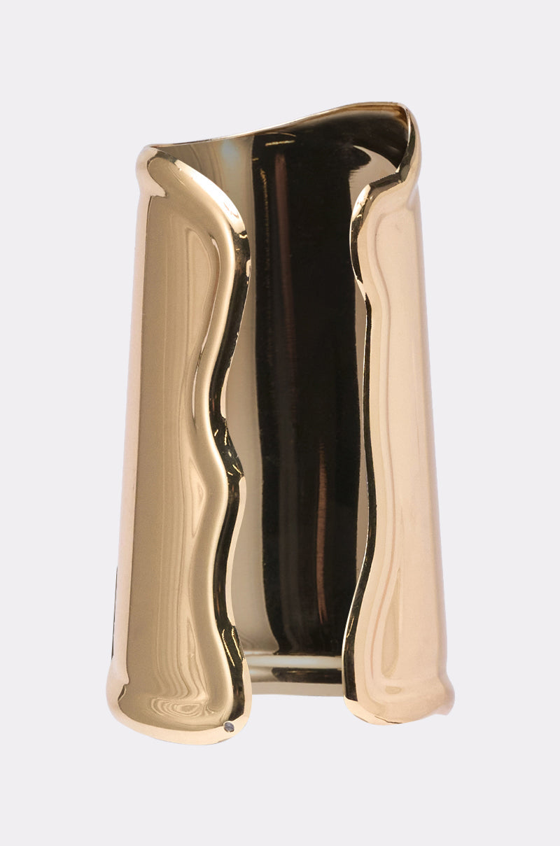 The OUTFIT COMPLETER CUFF is a gold, sculptural vase with an asymmetrical, wavy-edged design and glossy finish that stands out as a bold accessory against a plain light background. 2