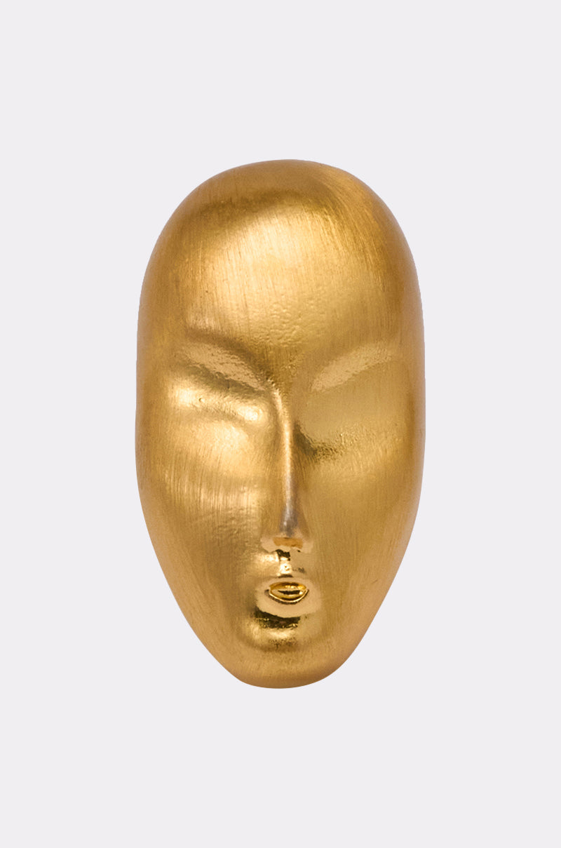 The OUTTA THIS WORLD RING features a smooth, golden, abstract 3D face design with closed eyes and parted lips, set against a plain light gray background. 1