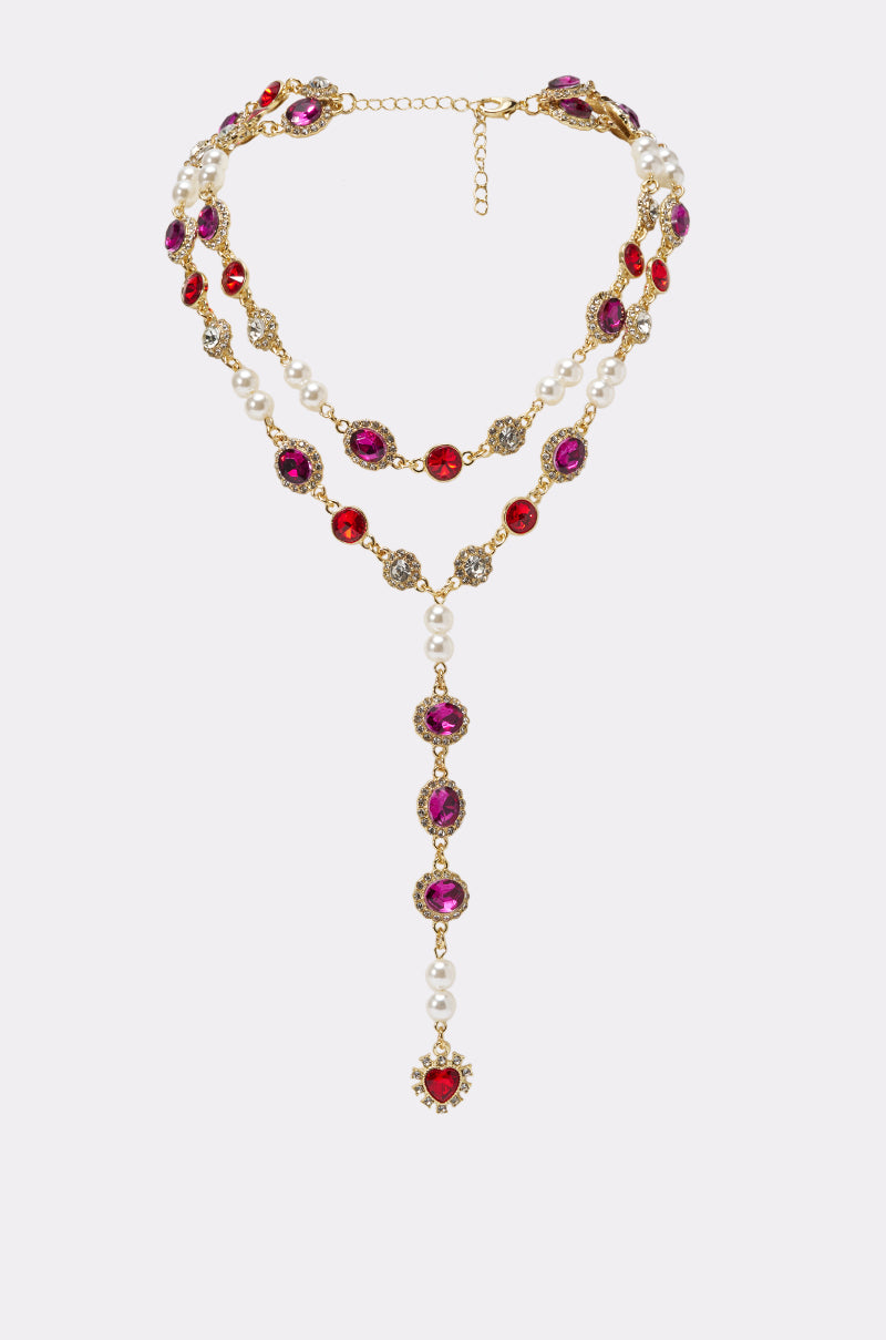 The WHATS YOUR VIBE NECKLACE is a double-stranded piece with gold links, purple and red gemstones, white pearls, a dangling jeweled pendant, and an adjustable chain closure.