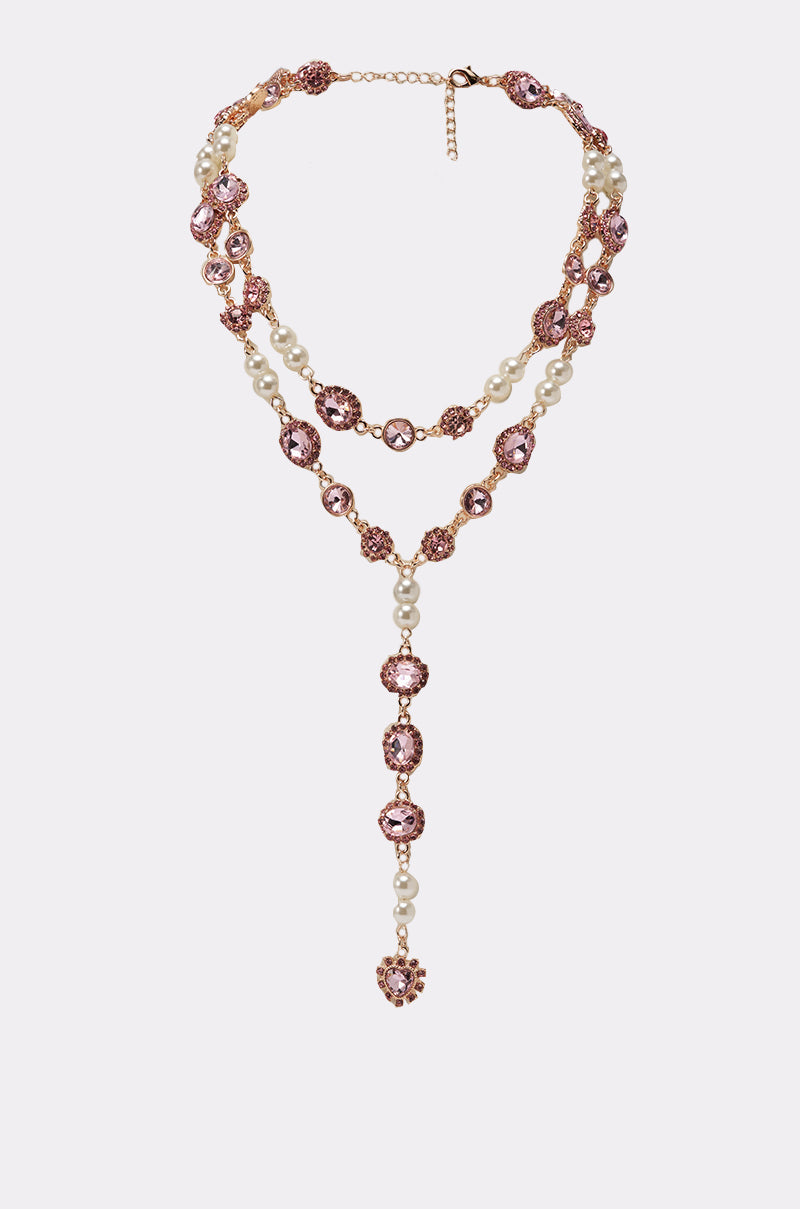 The UNDER THE LIGHTS NECKLACE is vintage-inspired, featuring pink gemstones and pearls in a Y-shaped drop. It has varying strand lengths connected by a gold chain and finished with an adjustable clasp. 1