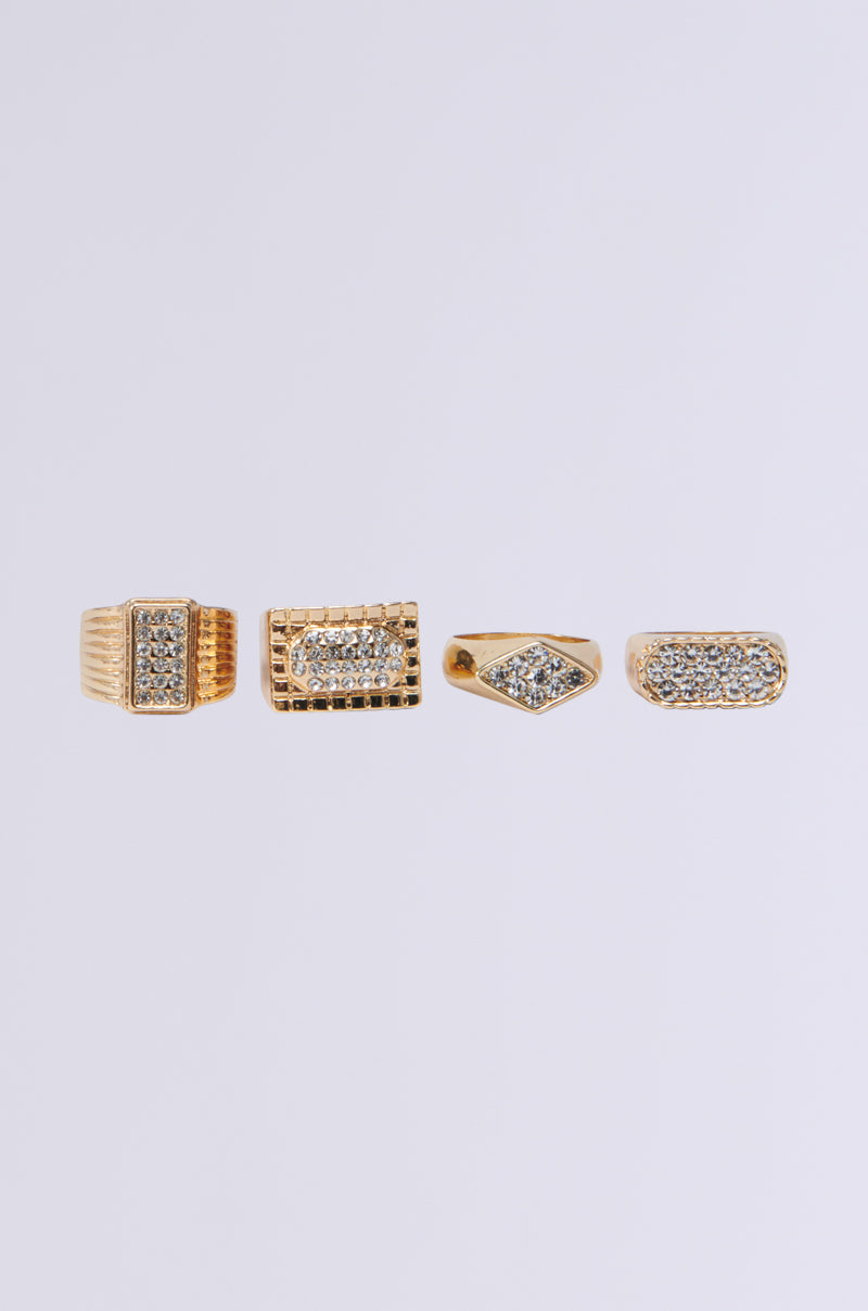 The EXPENSIVE TASTE RING SET features four gold geometric design rings adorned with rhinestones, exuding elegance and luxury against a plain white background, perfectly capturing sophisticated style.