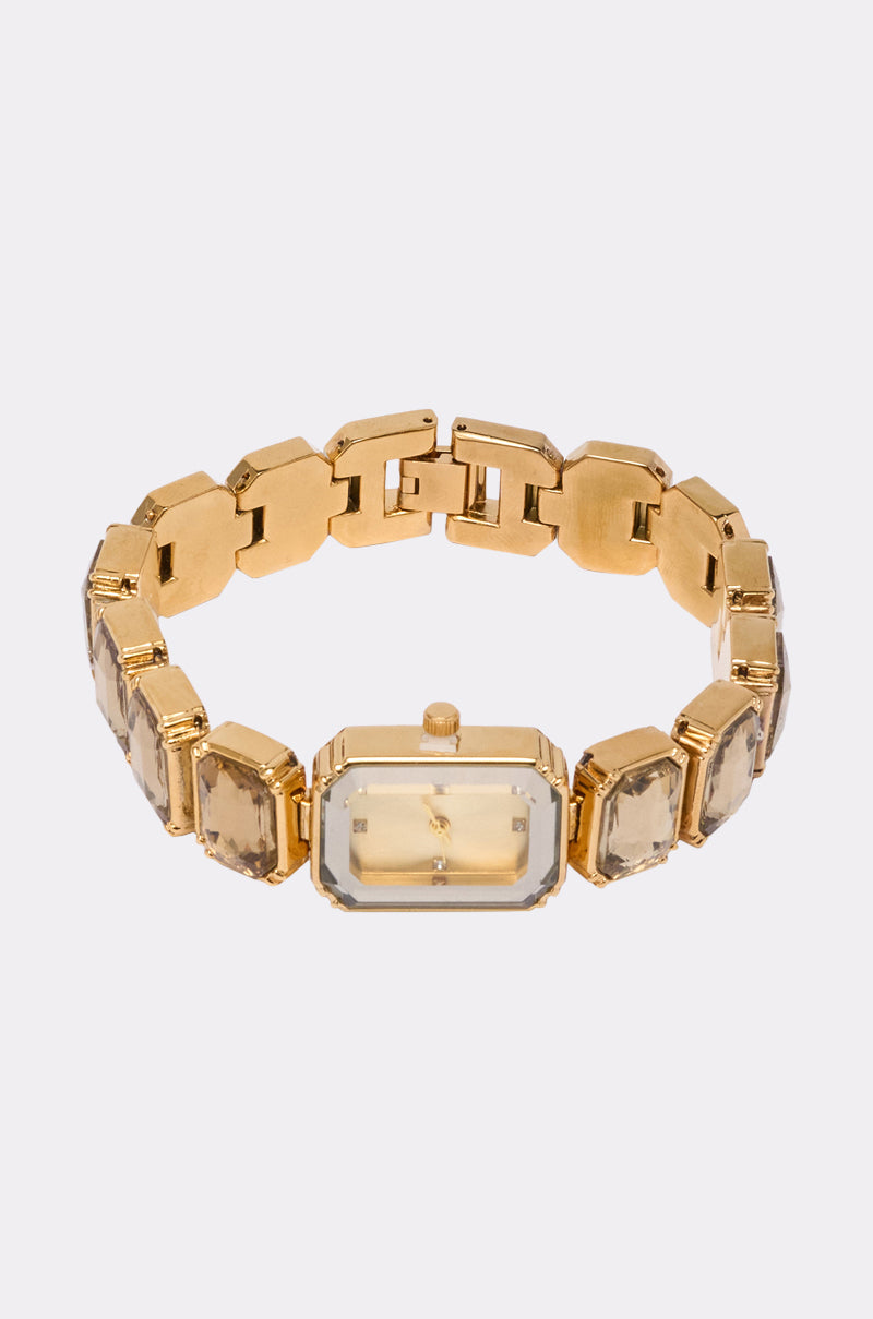 The SO GROOVY WATCH IN YELLOW features a retro-chic gold-tone rectangular face, matching gold band, and sparkling gemstones set in each link, all showcased on a plain white background. 3