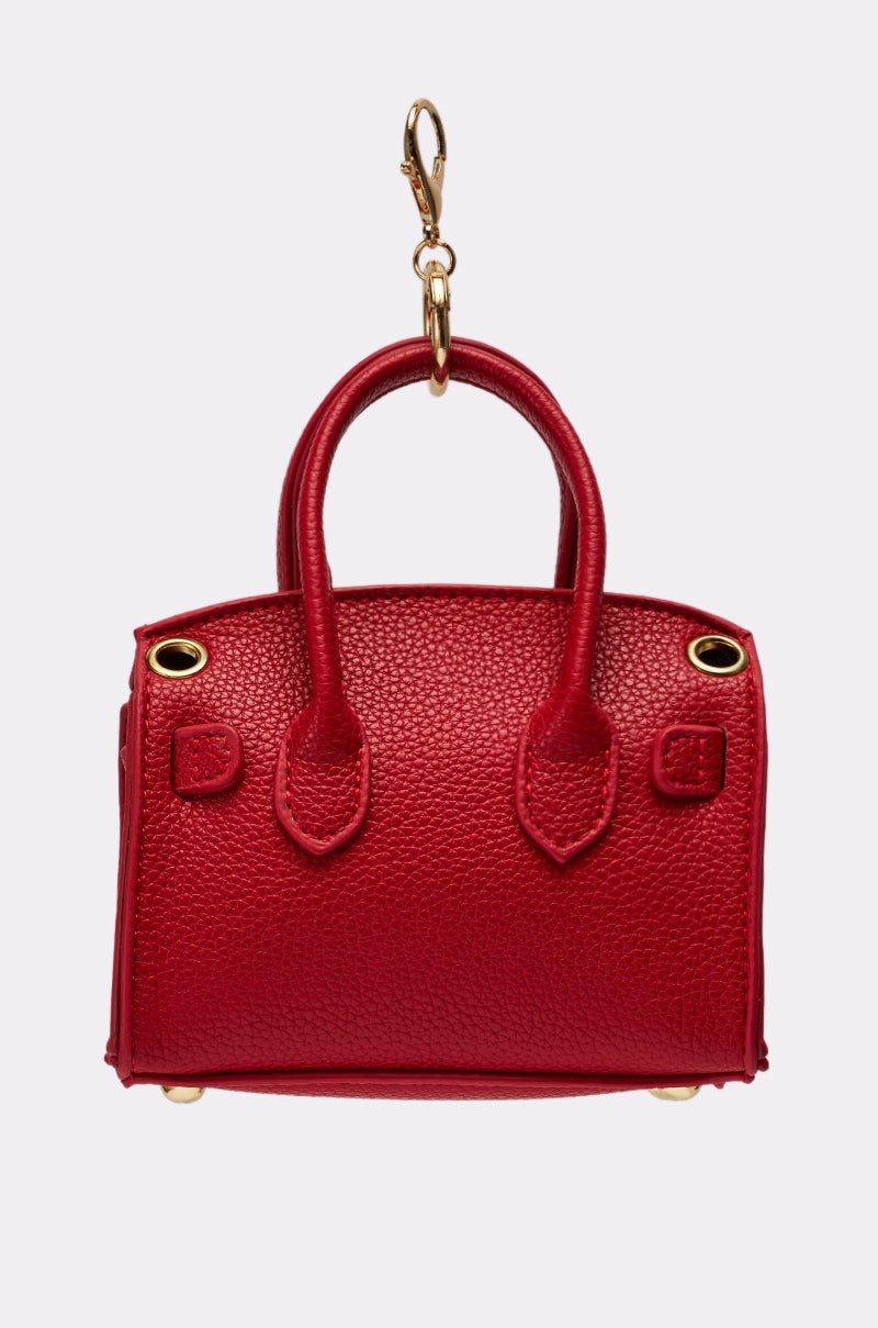The NEVER TOO BIG BAG KEYCHAIN is a small red textured mini purse keychain with gold hardware and clasp attachment, displayed against a plain white background. 3