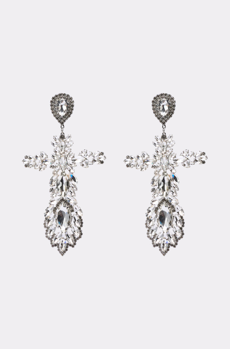 The WITH GRACE EARRING is a pair of ornate, silver-toned statement earrings featuring multiple clear gemstones in an intricate, symmetrical floral design, displayed against a plain light background.