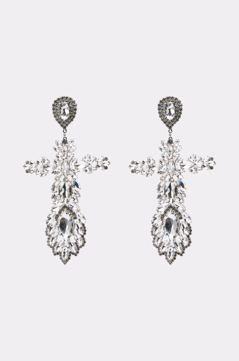 The WITH GRACE EARRING is a pair of ornate, silver-toned statement earrings featuring multiple clear gemstones in an intricate, symmetrical floral design, displayed against a plain light background. 1