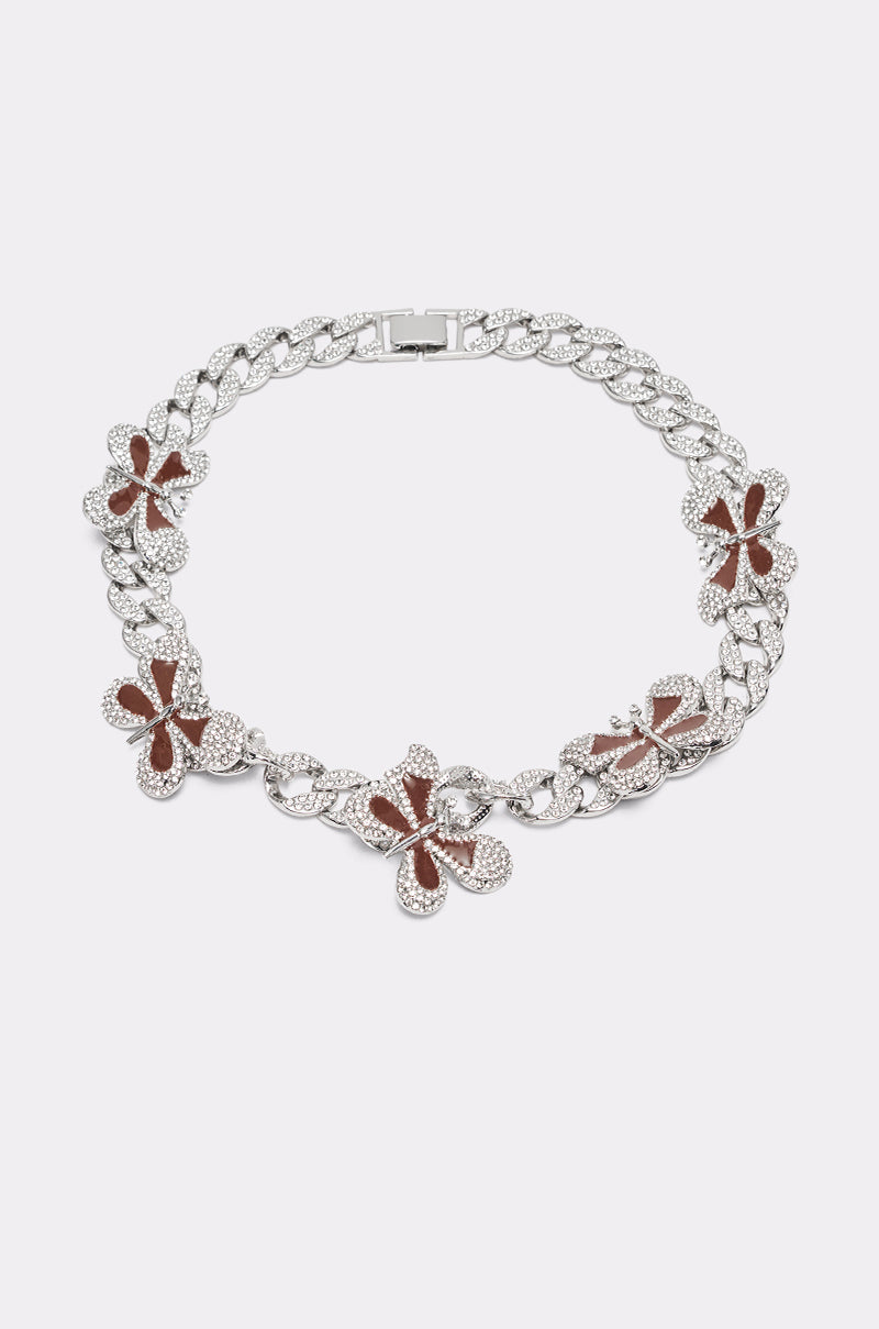 The LUXE BUTTERFLY NECKLACE is a silver Cuban link chain with five large butterfly pendants, each showcasing brown centers and sparkling accents, elegantly displayed on a simple light background. 1