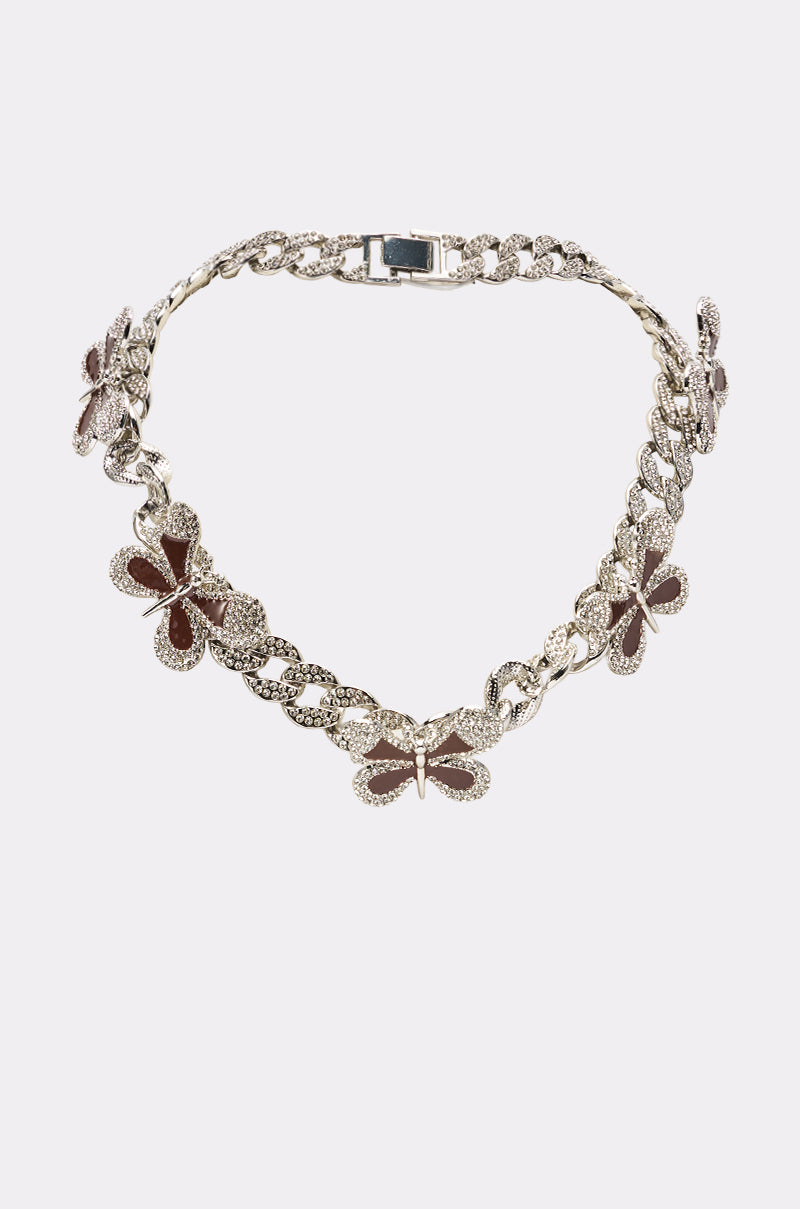 The LUXE BUTTERFLY NECKLACE features decorative charms, including a striking red enamel butterfly with brown enamel wings, displayed against a simple light background. 3