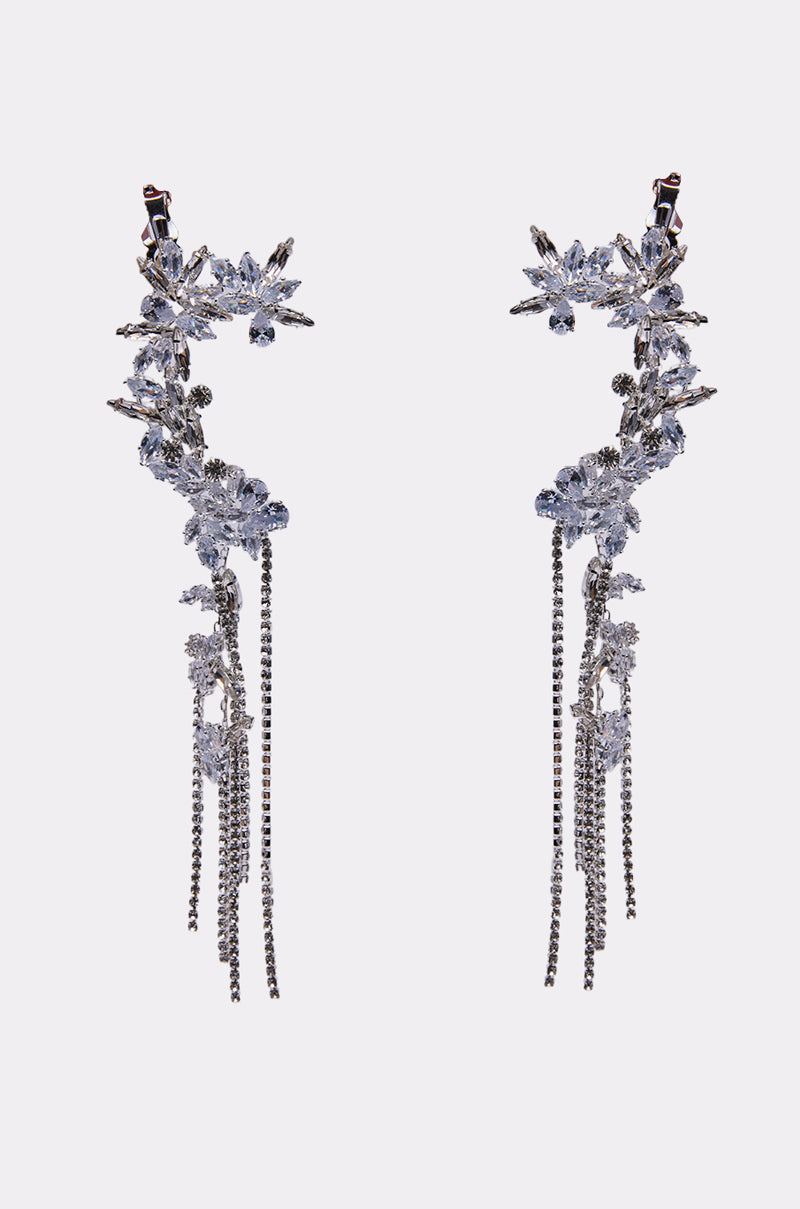 The KEL EARRING is an ornate, silver-toned accessory featuring sparkling crystals, floral designs, and multiple dangling rhinestone strands for a sophisticated, cascading look. 1