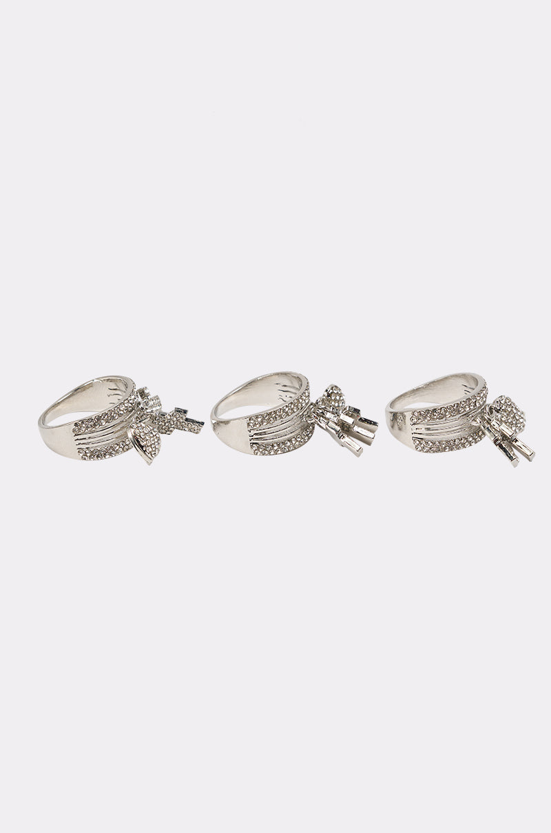 The ANGELS WITH ME RING SET features three silver statement rings with small clear stones and geometric designs, shown side by side on a plain white background. 2