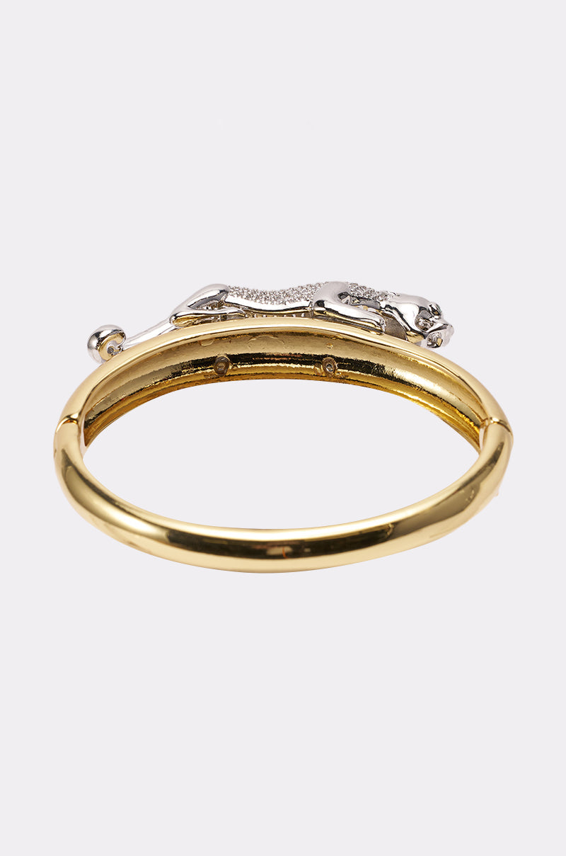 The JUMP ON IT BRACELET is a gold sculptural bangle featuring a silver-tone leopard adorned with small clear rhinestones, beautifully showcased against a plain white background. 3