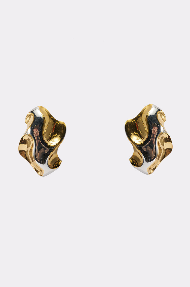 The MIXED FEELINGS EARRING features abstract, wavy designs in gold and silver metallic finishes, displayed against a plain light background. 0