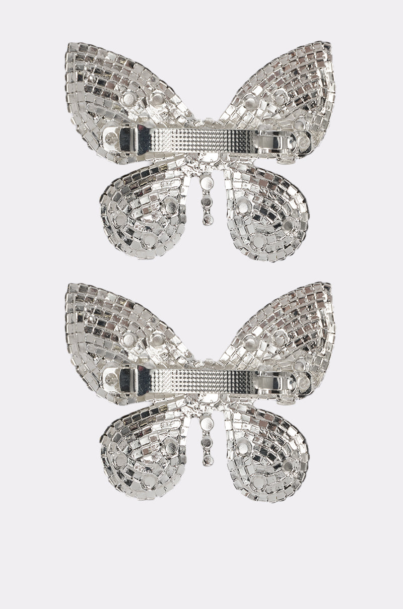 The FLY AWAY HAIR CLIP SET features two silver butterfly barrettes with shiny, mosaic-like crystal patterns, displayed vertically on a plain white background. 4