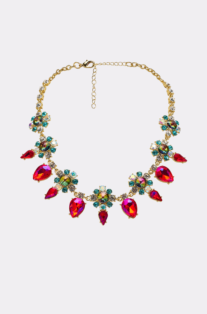 The FESTIVAL NECKLACE is a gold teardrop gem statement piece with bright red stones, blue and green clusters in a floral design, and an adjustable clasp for the perfect fit. 0