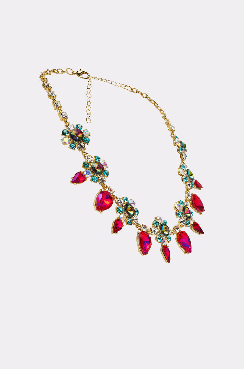 The FESTIVAL NECKLACE features a gold chain with teardrop gems, bold red ovals, and floral clusters of blue and green stones in dazzling arrangements. 2